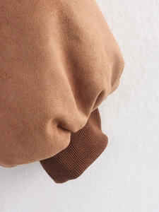 Detail eines kamelfarbenen Wildlederärmels mit dunkelbraunen Strickbündchen an dieser Jacke