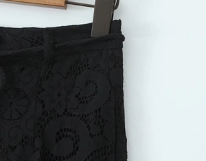Detail of black lace pants featuring intricate hollow patterns and a woven waistband