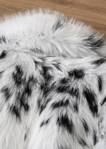 Gros plan de la texture de fourrure synthétique à motif dalmatien noir et blanc sur bois