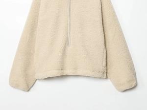Detailed texture of beige sherpa fleece pullover with half-zip closure and soft fabric