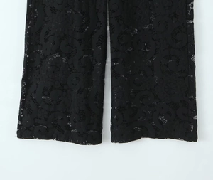 Close-up detail of black lace pants showing intricate floral hollow-out embroidery