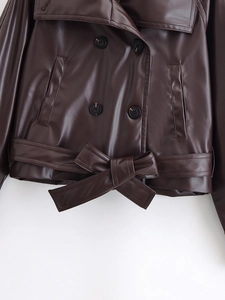 Detail of dark brown PU leather jacket featuring double-breasted buttons and tied waist belt