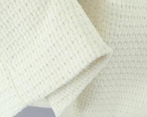 Macro view of white waffle knit fabric texture showing thick woven material for jackets