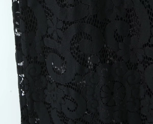 Close-up detail of black hollow lace fabric featuring intricate floral and scroll patterns