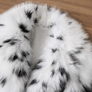 Veste en fausse fourrure à motif jacquard noir et blanc sur une surface en bois