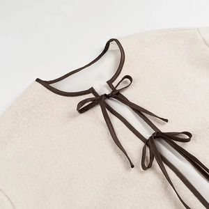Detail of soft beige fleece jacket featuring elegant brown ribbon bow tie neckline