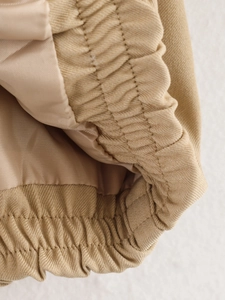 Macro shot of khaki bomber jacket showing elastic hem, twill fabric and silky lining detail