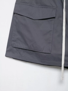 Close-up of deep grey cargo skirt with large flap pocket and cream braided drawstring