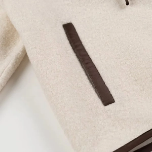 Close-up of fuzzy cream fleece texture with dark brown piping on outer pocket edge