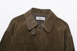 Detail of collared brown suede jacket with snap buttons and white brand neck label