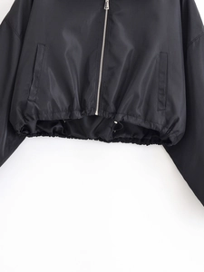 Detailansicht einer schwarzen kurzen Kordelzugjacke mit silbernem Reißverschluss und feiner Textur