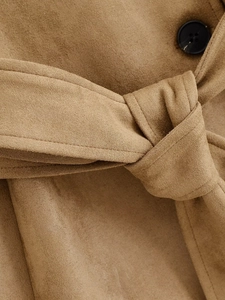 Detail of camel faux suede trench coat featuring a waist tie belt and dark button