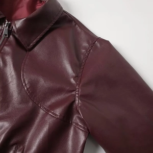 Macro detail of wine red PU leather texture, lapel collar, and silver metal zipper