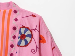 Close-up of pink linen kimono cardigan featuring intricate floral embroidery and striped lining