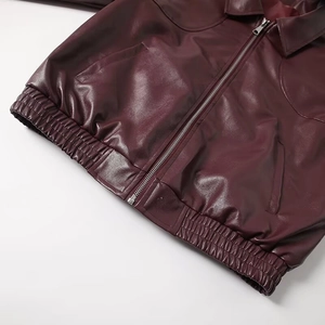 Detailed close-up of a burgundy faux leather jacket featuring a silver metal zipper closure