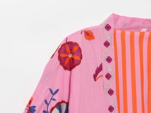 Detail of pink embroidered linen cardigan showing floral patterns and striped lining