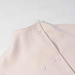 Detail of light pink wool coat featuring stand collar and matching round buttons