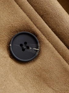 Close-up of marble texture button and camel faux suede fabric on autumn trench coat
