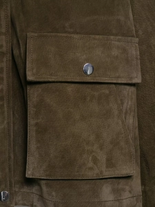Detailed view of suede texture flap pocket and metallic button on olive jacket