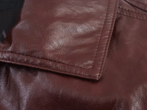 Macro shot of high-quality wine red leather texture and fine stitching on the cropped jacket