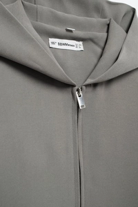 Détail d'une veste gris foncé montrant la texture sergé fine et la fermeture éclair argent
