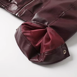 Detailed close-up of wine red faux leather jacket with metal zipper and snap button