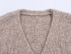 Close-up of the plush V-neck knit fabric texture and shoulder detail on a beige cardigan