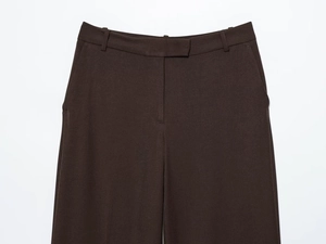 Detail of dark brown high-waisted trousers with belt loops and side pockets