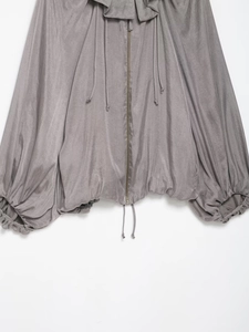 Detail of grey zip-up bomber jacket featuring ruffled collar and adjustable drawstring hem