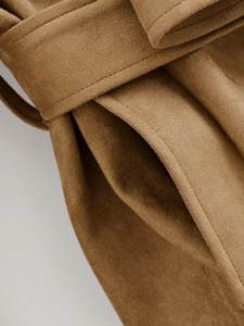 Detailed close-up of camel suede coat showing pocket stitching and waist belt texture