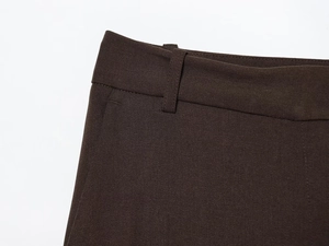 Detailed close-up of brown twill trousers waist with belt loops and fine stitching