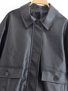 Close-up of black faux leather jacket featuring grain texture and buttoned flap pockets