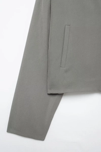 Vue détaillée de la veste grise montrant la poche, les coutures et la texture du tissu