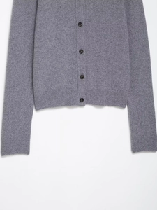 Detailed macro view of gray knitted cardigan fabric texture with black buttons and ribbed hem