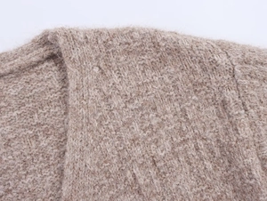 Close-up of light brown and beige knit fabric with fuzzy wool texture and flat stitch