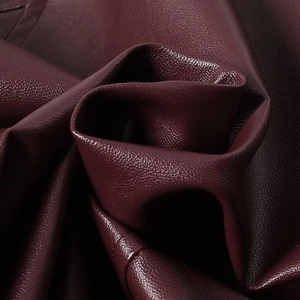 Close-up of wine red faux leather fabric with litchi grain texture for autumn jacket