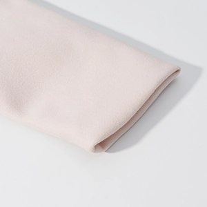 Close-up of premium light pink wool coat fabric showing fine texture and clean cuff seams