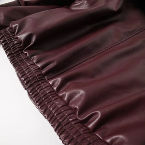 Detail of the elastic hem on a dark burgundy PU leather jacket with clean stitching