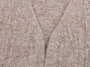 Macro detail of the fuzzy knit texture and V-neckline of this chunky oversized cardigan