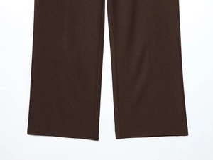 Detailed close-up of dark brown trousers showing refined twill fabric and neat hem stitching