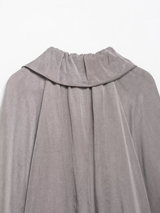 Detailed view of grey silk-like bomber jacket featuring elegant pleated high collar design