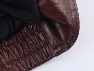 Detailed macro view of dark brown faux leather texture with elasticated cuff and lining