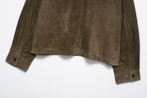 Detailed close-up of dark brown suede jacket hem and cuffs with metal snap buttons