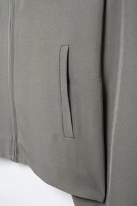 Gros plan sur la texture en sergé gris foncé et la poche latérale d'une veste courte