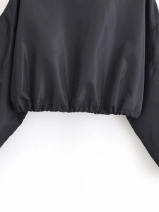 Detail des elastischen Saums der kurzen Jacke und glatte schwarze Stofftextur auf Weiß