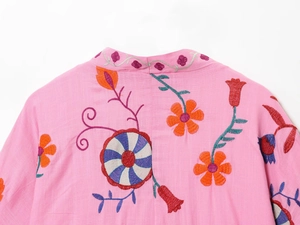Detailed view of colorful floral embroidery on pink cotton-linen bohemian shirt