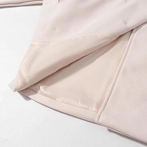 Detailed macro view of beige wool coat hem showing smooth lining and fine fabric texture