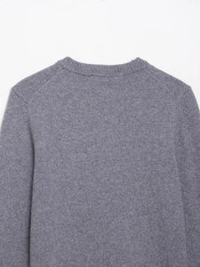Close-up of the grey knit sweater featuring a ribbed crew neck and raglan sleeve stitching