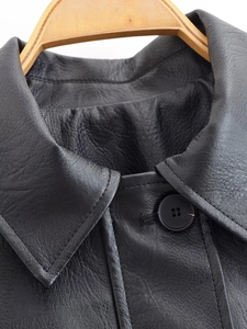Detail shot of the lapel and black button on a PU leather baseball jacket for women