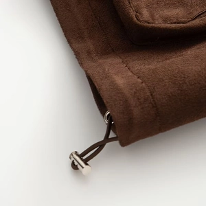 Dettaglio del bordo in camoscio marrone scuro con cordoncino e chiusura in metallo